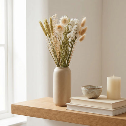 Trockenblumen in Vase auf Regal mit Büchern und Kerze