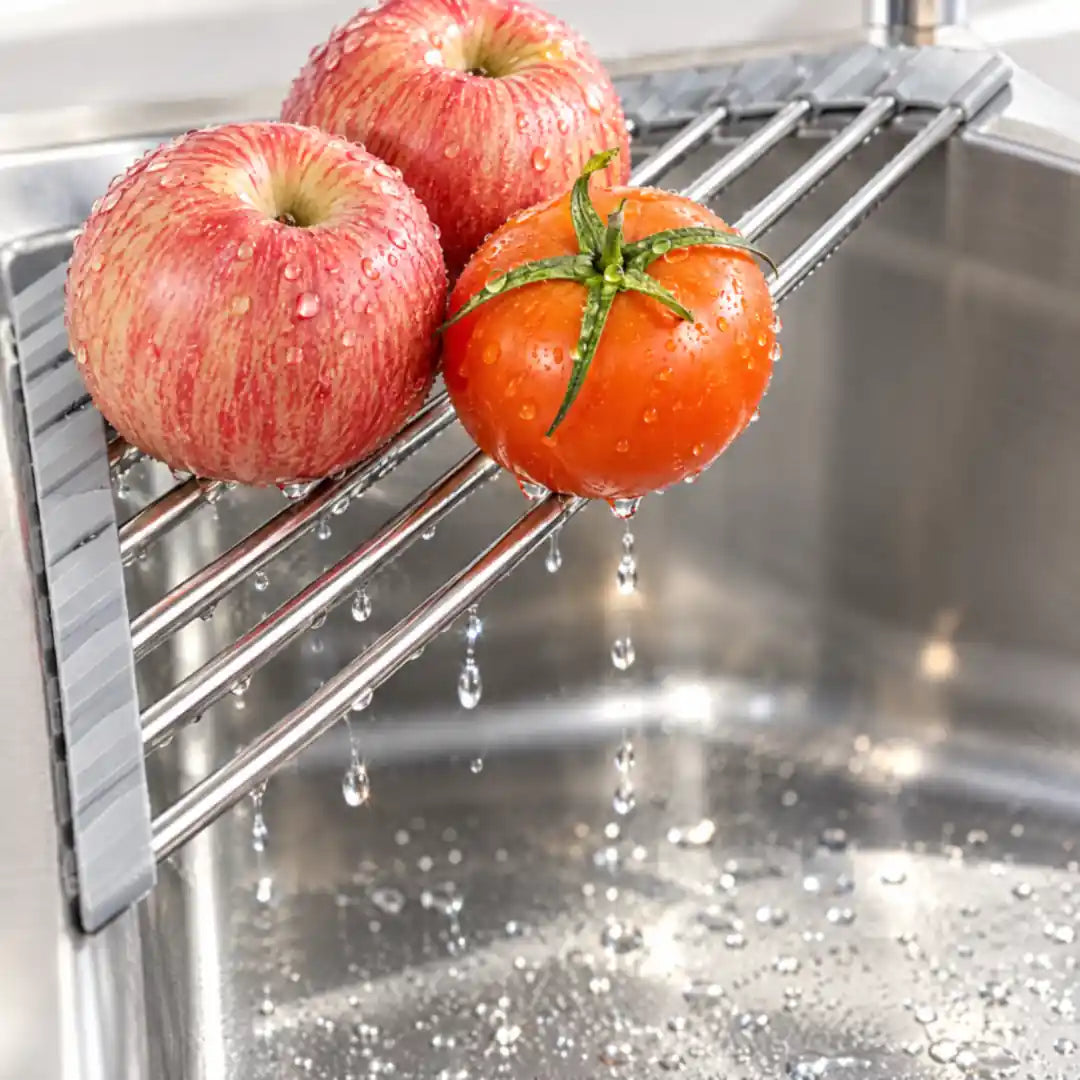 Gewaschene Äpfel und Tomate tropfen auf dem Abtropfgestell ins Spülbecken ab