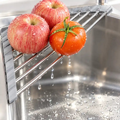 Gewaschene Äpfel und Tomate tropfen auf dem Abtropfgestell ins Spülbecken ab