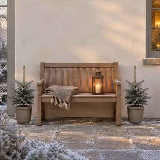 Zwei Blaufichten in greigen Kübeln neben einer Holzbank auf der Terrasse im Winter