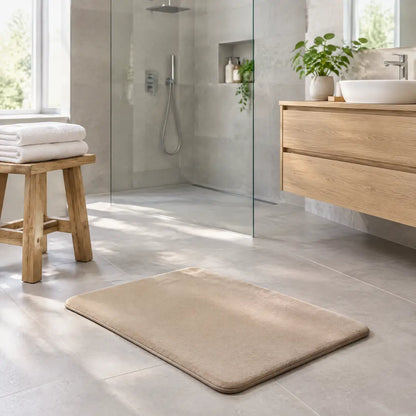 Beige Badematte vor einer bodengleichen Dusche im hellen Bad