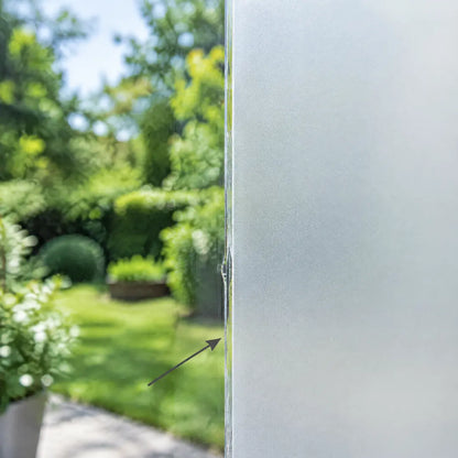 Fensterscheibe halb mit Sichtschutzfolie beklebt, daneben freier Blick in den Garten