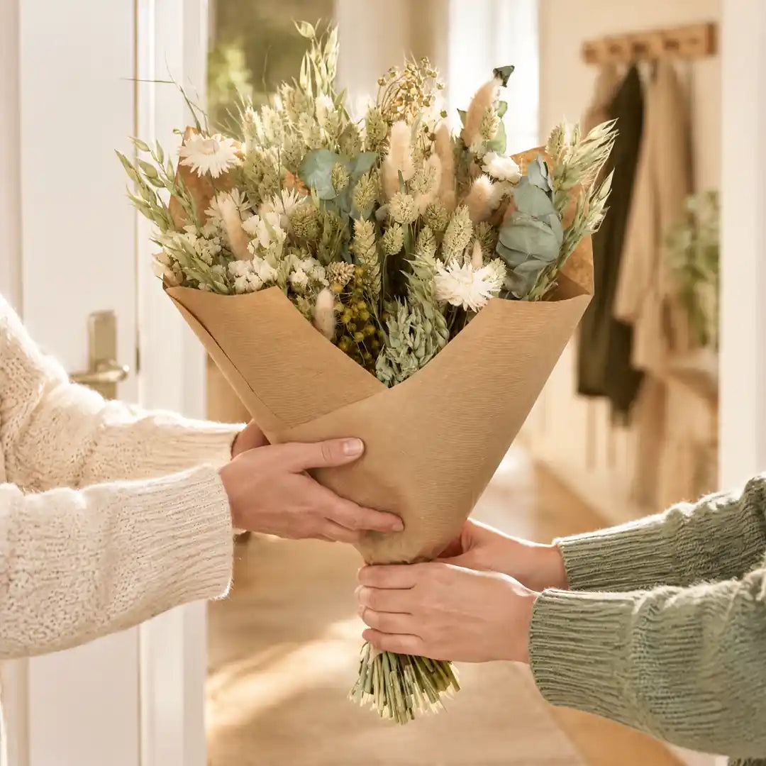 Trockenblumenstrauß in Kraftpapier als Geschenk überreichen