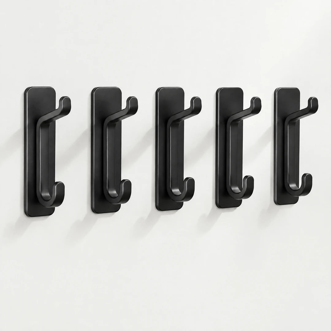 Fünf schwarze Klebehaken in einer Reihe an heller Wand