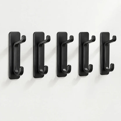 Fünf schwarze Klebehaken in einer Reihe an heller Wand