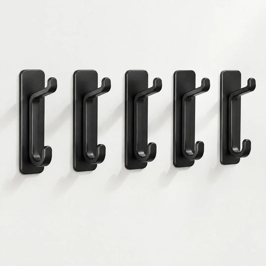 Fünf schwarze Klebehaken in einer Reihe an heller Wand
