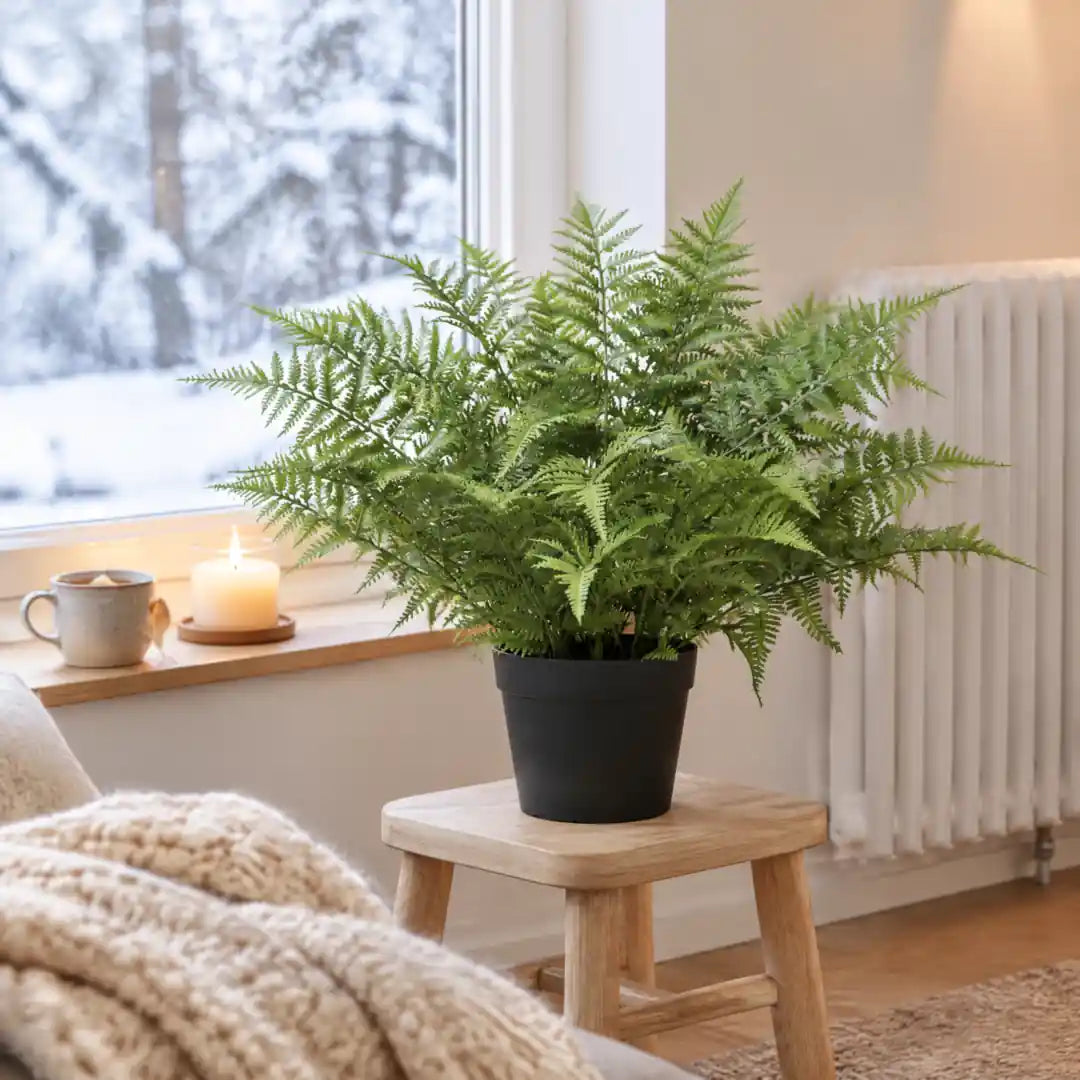 Frischer Kunstfarn neben dem Heizkörper im Winter