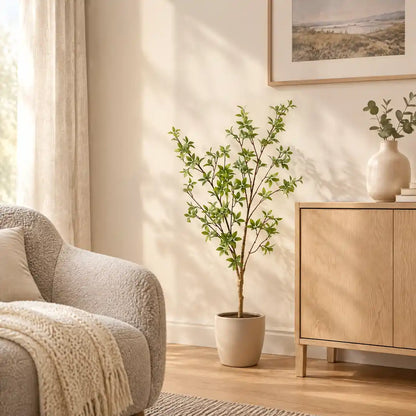 Künstliche Myrte im beigen Übertopf neben Sideboard und Sessel im Wohnzimmer