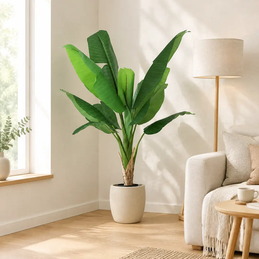 Künstlicher Bananenbaum im hellen Wohnzimmer neben Sofa und Stehlampe