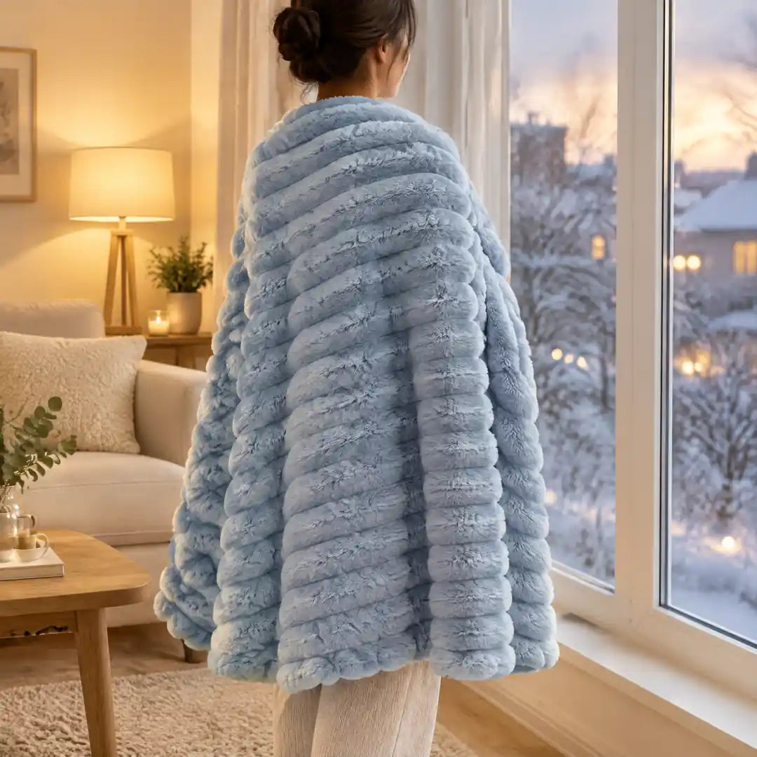Hellblaue Kuscheldecke locker über den Schultern am Winterfenster