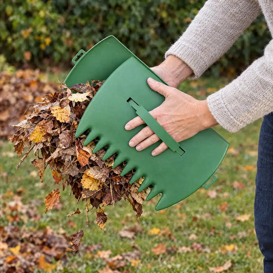 Laubgreifer im Einsatz: Hände heben mit den Laubgreifern einen Packen Herbstlaub vom Rasen