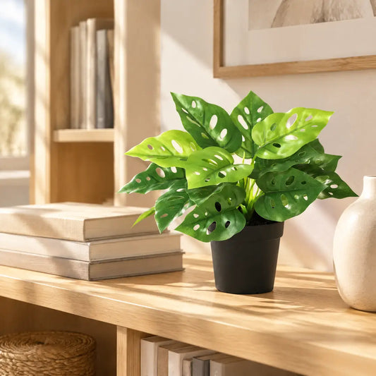 Künstliche Monstera auf einem Holzregal im Wohnzimmer zwischen Büchern
