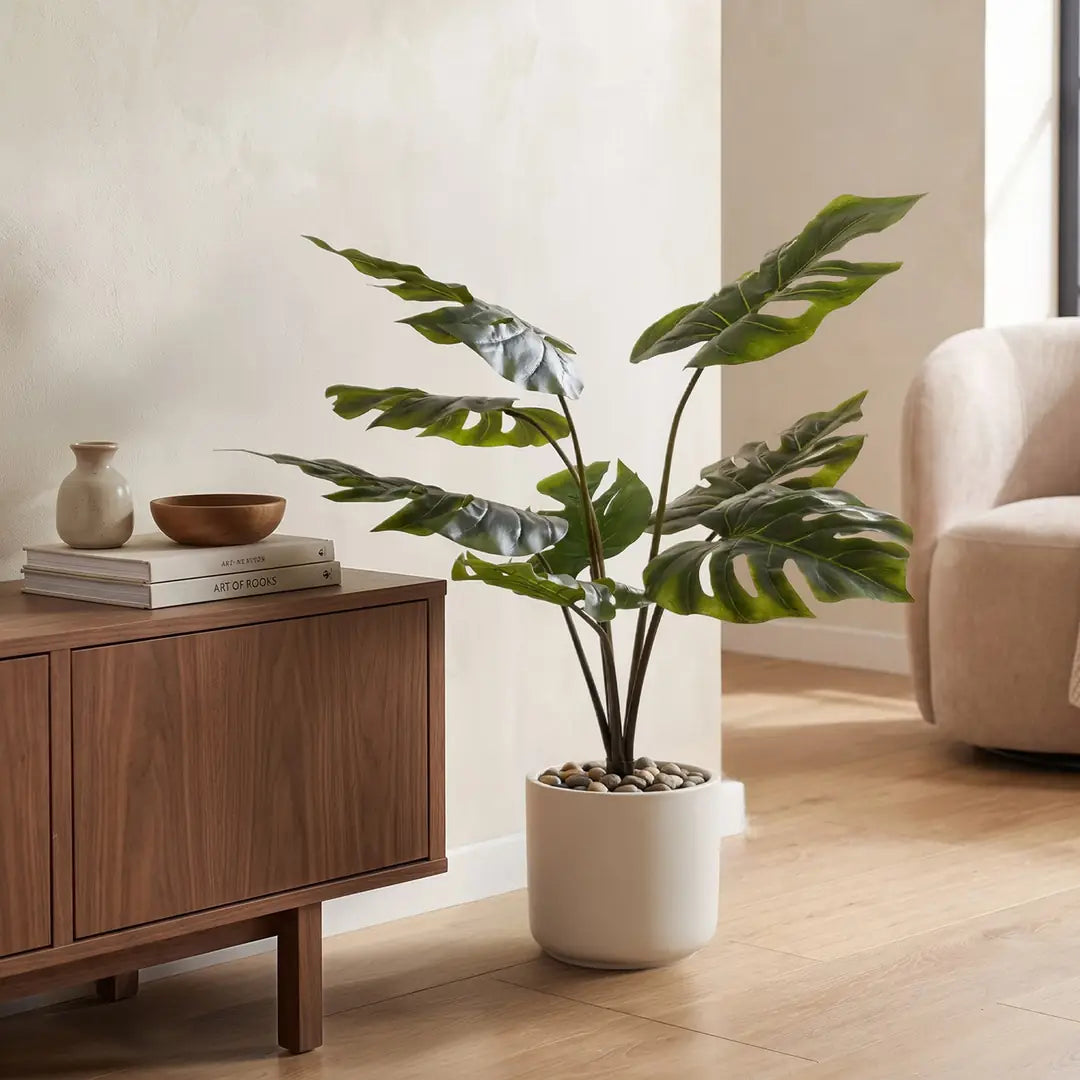 Künstliche Monstera 65 cm im weißen Übertopf neben dem Sideboard