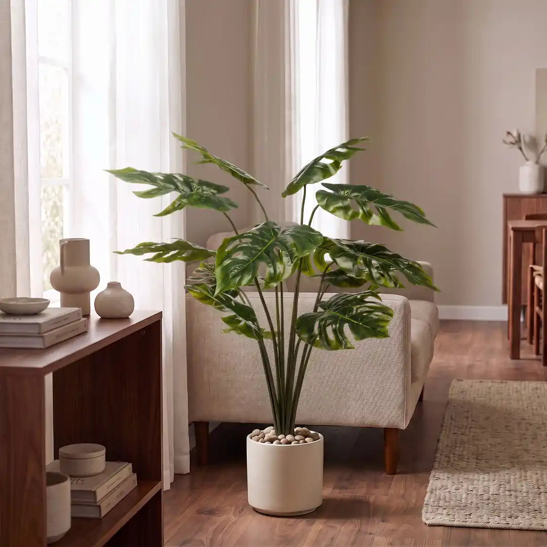 Künstliche Monstera 95 cm im Übertopf vor dem Sofa