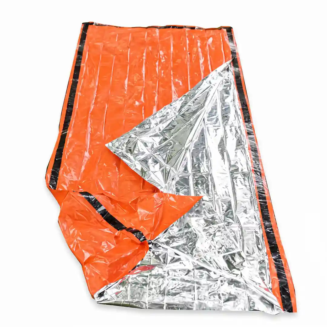 Aufgeschlagener Notfallschlafsack, aluminisierte Innenseite reflektiert die Körperwärme