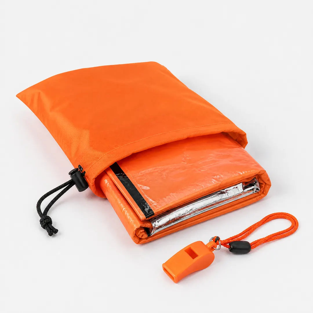 Geöffneter Packsack mit gefaltetem Notfallschlafsack und Signalpfeife