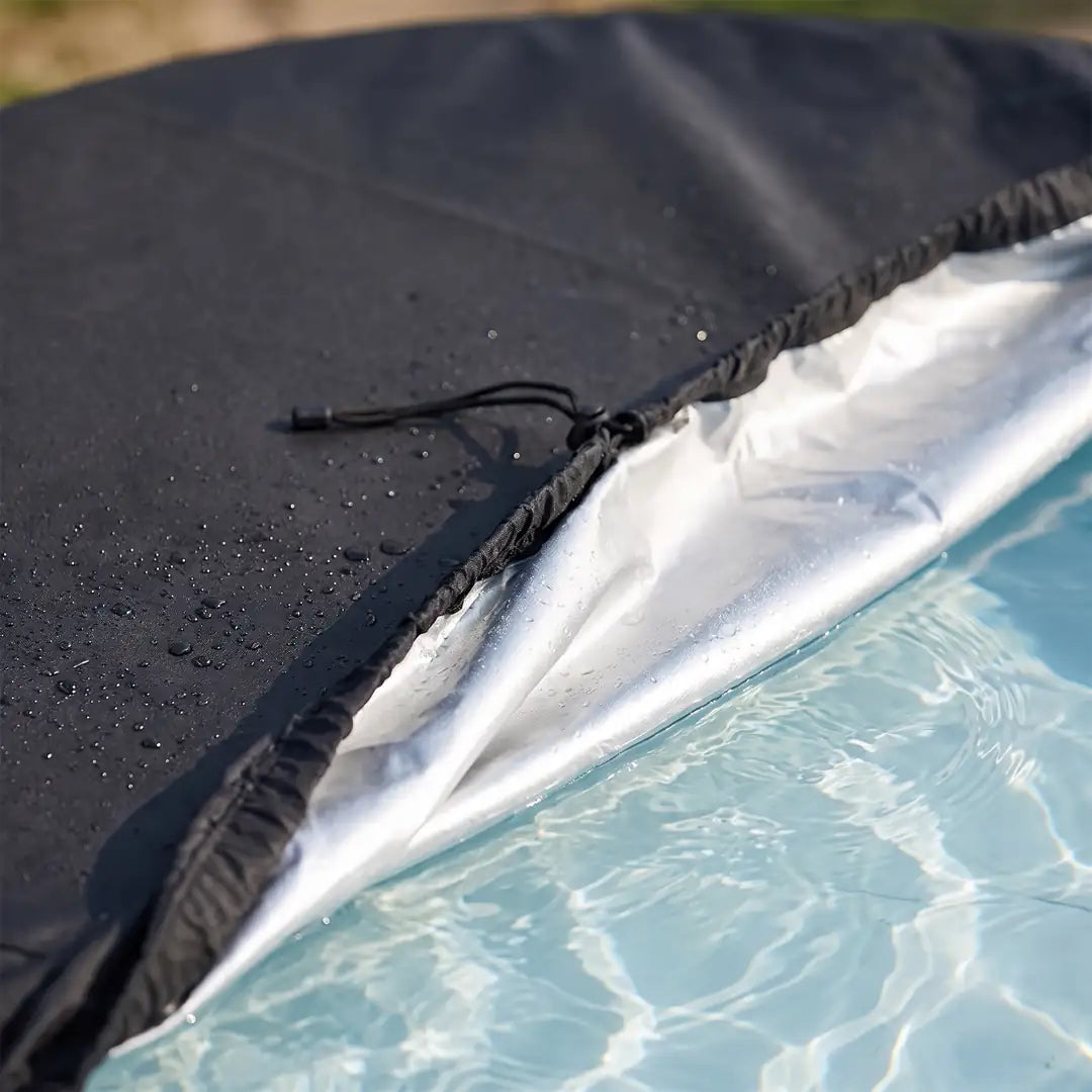 Poolabdeckung zurückgeschlagen: matte schwarze Außenseite und silberne Innenseite, darunter klares Wasser