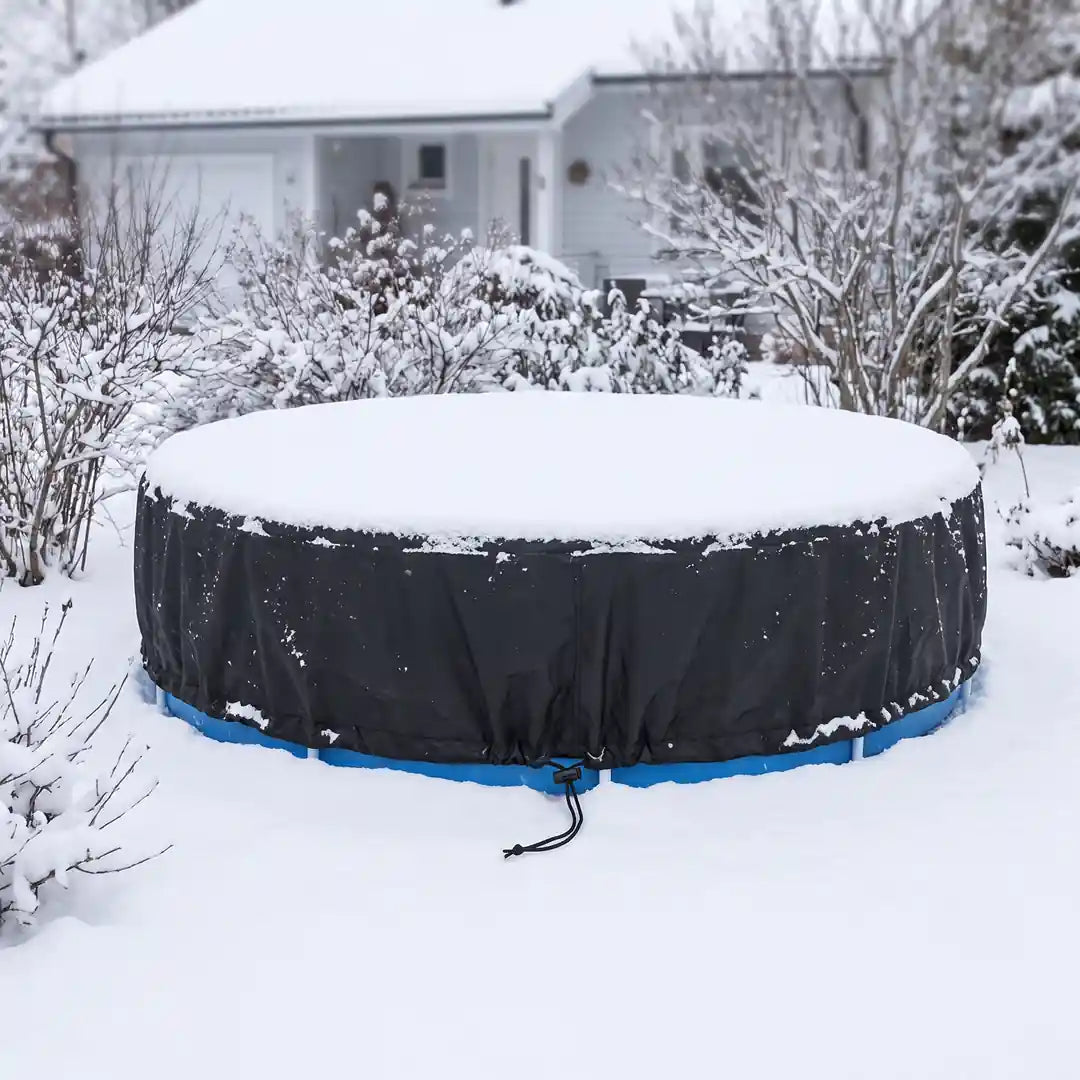 Poolabdeckung im Winter: dünne Schneeschicht auf der gespannten schwarzen Plane