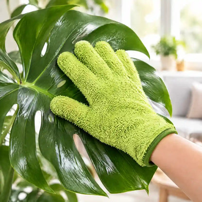 Hand im grünen Mikrofaser-Handschuh streift über ein Monstera-Blatt