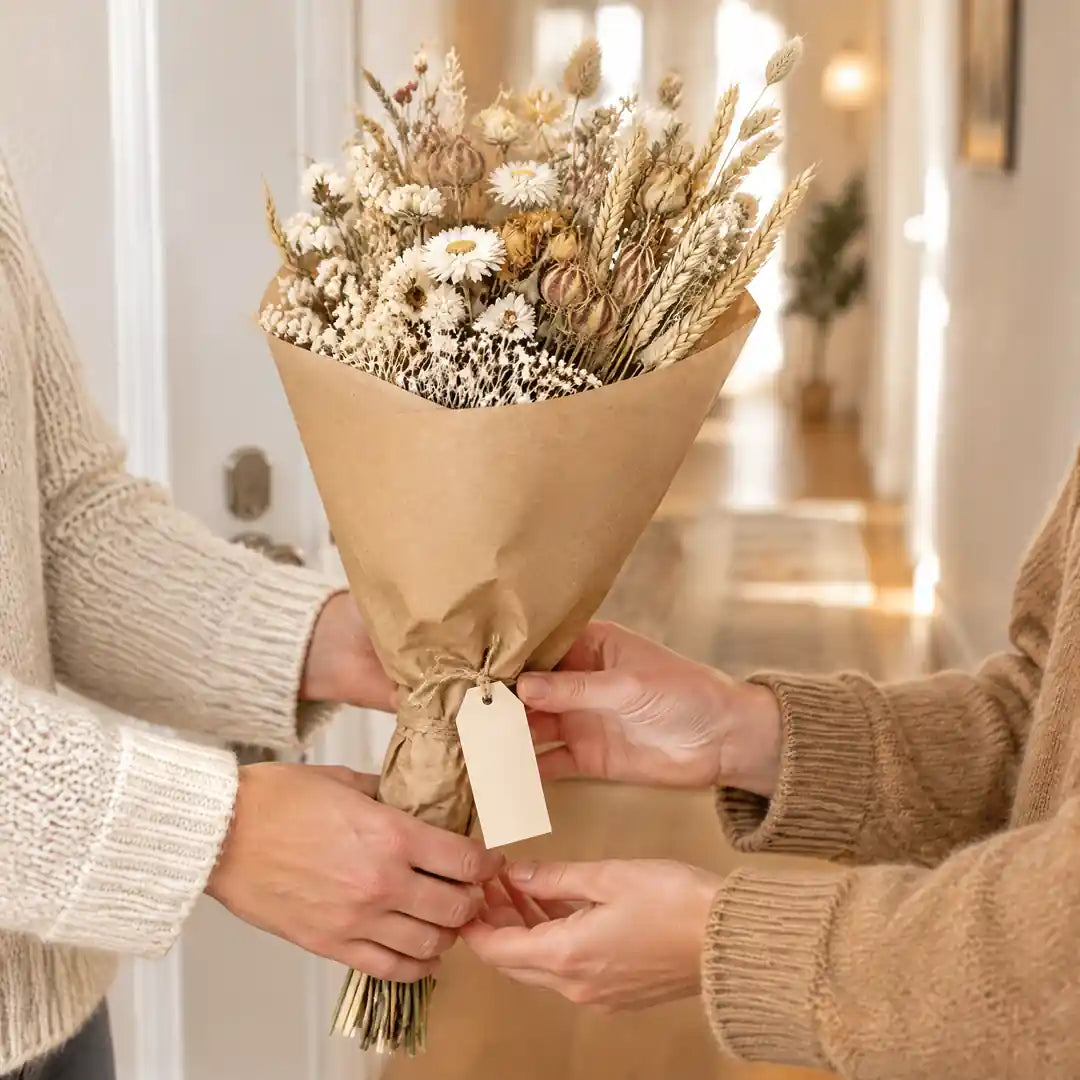 Trockenstrauß in Kraftpapier wird als Geschenk überreicht